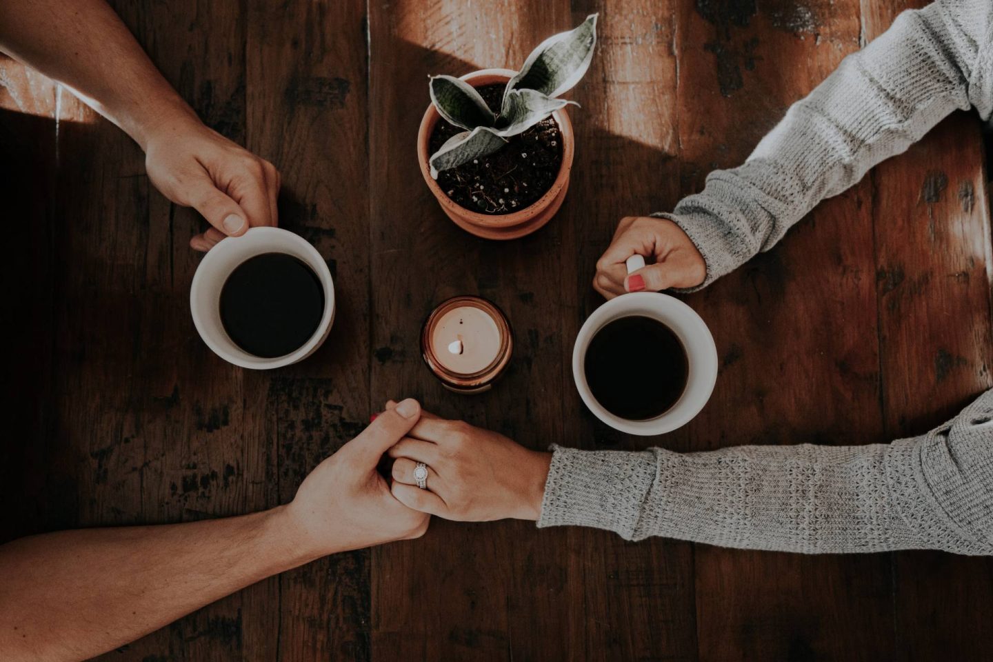 Couple with coffee cups holding hands